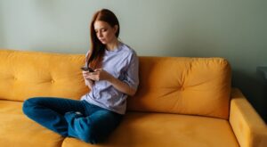 Portrait,Of,Frustrated,Young,Woman,Sitting,On,Yellow,Couch,Looking