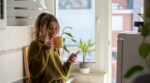 Shot,Of,A,Young,Woman,Drinking,Tea,And,Using,Smartphone
