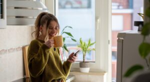 Shot,Of,A,Young,Woman,Drinking,Tea,And,Using,Smartphone