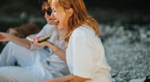Two,Friends,Laughing,And,Enjoying,Watermelon,During,A,Sunny,Picnic