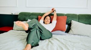 Young,Woman,Waking,Up,,Stretching,Arms,And,Legs,,Feeling,Comfortable